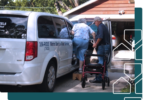 Man helping elderly woman into ride service vehicle