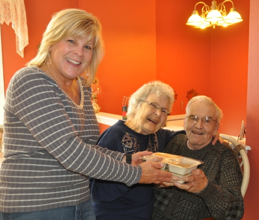 A volunteer delivering food to an elderly couple